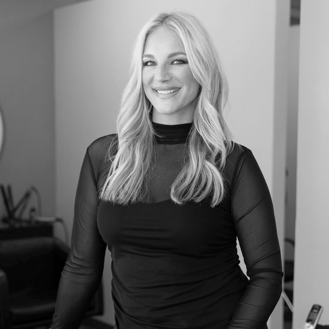 Black and White photo of a woman with long, light hair and heavy mascara. She is wearing a sheer, mock turtleneck over a simple tanktop.