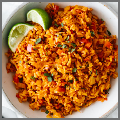 Vibrant mexican rice with two slices of lime garnishing it.